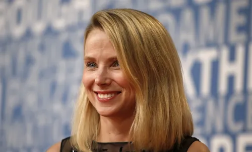 ماريسا ماير الرئيسة التنفيذية السابقة لشركة Yahoo بابتسامة في مؤتمر، تعبير عن دور الذكاء الاصطناعي في تربية الأطفال والتقنيات الحديثة.