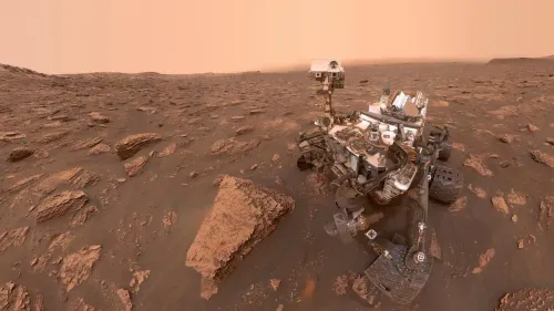 المركبة الجوّالة Curiosity على سطح المريخ وسط تضاريس صخرية حمراء، توضح تقدمها في استكشاف جبل شارب ومسارها الطويل منذ 2012.