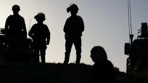 جنود إسرائيليون يقفون في الظل، بينما تظهر امرأة فلسطينية تسير بالقرب منهم، مما يعكس التوتر والواقع الصعب الذي تعيشه النساء في السجون.