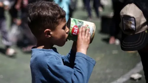 طفل فلسطيني يشرب من علبة طعام في غزة، وسط أزمة إنسانية حادة بسبب نقص الغذاء نتيجة الحصار. تعكس الصورة معاناة الأطفال في ظل الظروف القاسية.