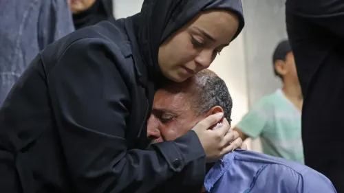 امرأة فلسطينية تعانق رجلاً يبكي بحرقة في مشهد يعكس الحزن العميق لعائلة محمد أبو خمّاش بعد فقدانه في خط النار الإسرائيلي في غزة.
