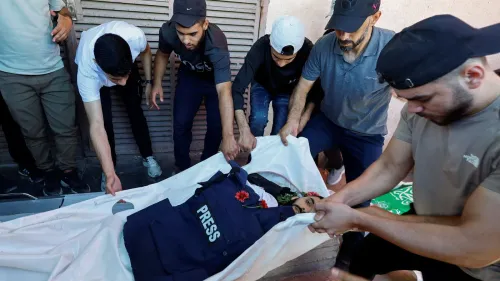 رجال يحملون جثمان الصحفي الفلسطيني أحمد وشاح مرتدياً سترة الصحافة وسط حزن في جنازة بغزة بعد اغتياله بغارة إسرائيلية.