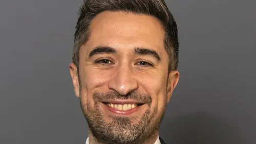 صورة لنائب بريطاني مبتسم، يظهر في إطار رسمي، وسط جدل حول إلغاء زيارته لمدرسة بسبب معارضة مؤيدي فلسطين.