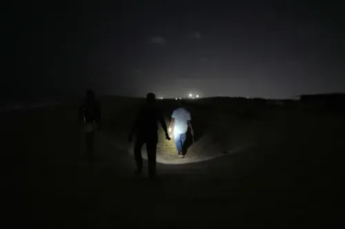 متطوعون يسيرون على شاطئ مظلم في تشيناي ليلاً، يحمل أحدهم مصباحاً للبحث عن أعشاش السلاحف البحرية وحمايتها.