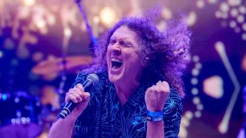 الفنان الكوميدي "Weird Al" Yankovic يغني بحماس على المسرح مع شعره المجعد وسط أضواء ملونة، في لحظة احتفال بتكريمه الفلكي.