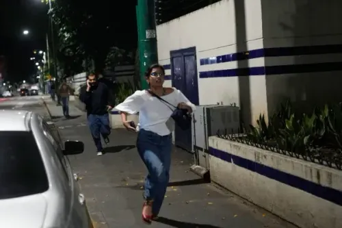 امرأة ترتدي قميصًا أبيض وسروال جينز، تركض في شارع مظلم في كاراكاس، بينما يظهر رجل خلفها. الانفجارات تثير حالة من الذعر.