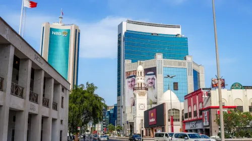 صورة لمدينة المنامة في البحرين، تظهر مباني حديثة مع لافتات ضخمة للملك حمد بن عيسى آل خليفة، تعكس التوترات السياسية الحالية.