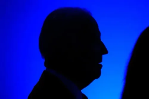 ظل شخصي يظهر في إضاءة زرقاء، يعكس جوًا من التأمل والجدية، مرتبطًا بخطاب بايدن حول التحديات السياسية وحرية التعبير.