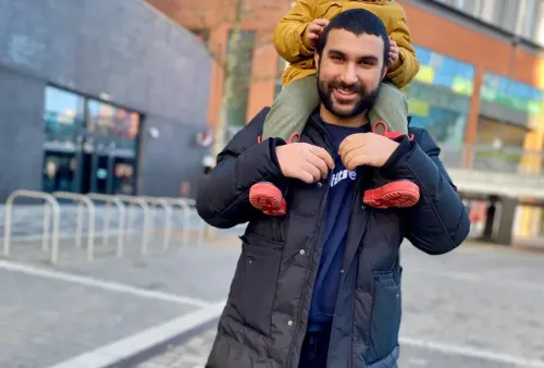 سامي حمدي يحمل طفلاً على كتفيه في لندن بعد إطلاق سراحه من الاحتجاز في الولايات المتحدة، معبراً عن فرحته بلقاء أسرته مجدداً.