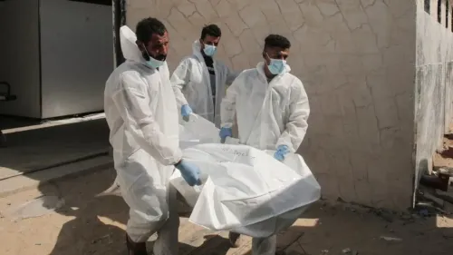 رجال يرتدون ملابس واقية يحملون جثمانًا مغطى في منطقة تتسم بالدمار، مما يعكس الظروف القاسية التي يواجهها الفلسطينيون في مراكز الاحتجاز.