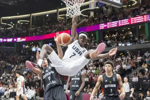 ديبانتسا، لاعب كرة سلة أمريكي، يسجل نقطة خلال مباراة دولية، مع جمهور كبير في الخلفية، مما يبرز مهاراته الرياضية العالية.