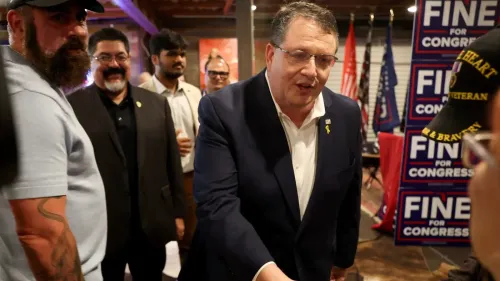 راندي فاين، النائب الجمهوري، يتحدث مع مؤيديه خلال حدث انتخابي، مع لافتات تدعمه في الخلفية.