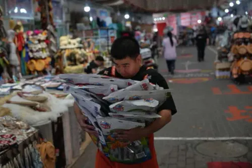 شاب يحمل أكياسًا مليئة بالمنتجات في سوق مزدحم بمدينة ألتاي، شينجيانغ، حيث تتجلى الأنشطة التجارية والتعاون الاقتصادي.