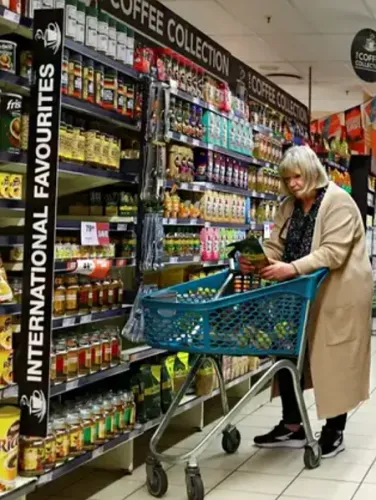 واجهة متجر AH Louis مزينة بأضواء وزينة عيد الميلاد، مع شخصية باليه ترتدي زيها أمام المدخل، تعكس أجواء الاحتفال.