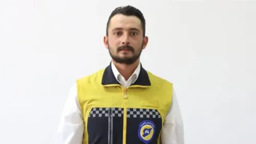 شاب سوري يرتدي زي الخوذ البيضاء للإنقاذ، يعكس قضية وفاة محمد غميرة في الحجز ومطالبات حقوق الإنسان بمحاسبة المسؤولين في سوريا.