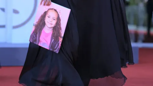 امرأة ترتدي ملابس سوداء تحمل صورة للطفلة الفلسطينية هند رجب، التي قُتلت في غزة، في فعالية تسلط الضوء على قضيتها.