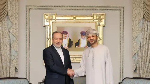 وزير الخارجية العُماني بدر بن حمد البوسعيدي يتصافح مع مسؤول إيراني، خلفهم صورة تاريخية، خلال مناقشات حول السلام في المنطقة.