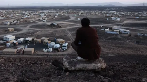 رجل يجلس على صخرة مطلًا على مخيم للنازحين في لحج، حيث تعيش العائلات الهاربة من النزاع في اليمن.