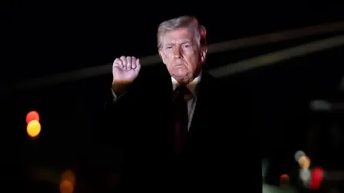 ترامب يرفع يده بإشارة قوية، مع خلفية مضاءة خافتة، معبرًا عن مواقفه حول الاستيلاء على النفط الإيراني.