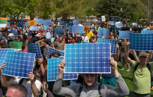 محتجون يحملون لافتات شمسية خلال فعالية بيئية، تعبيراً عن دعمهم لمبادرات الطاقة المتجددة في يوم الأرض.