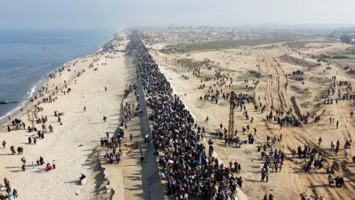 مئات الأشخاص يسيرون على شاطئ غزة، حيث يظهر المشهد كثافة الحشود في رد فعل على التهديدات الأمريكية بتهجير الفلسطينيين.