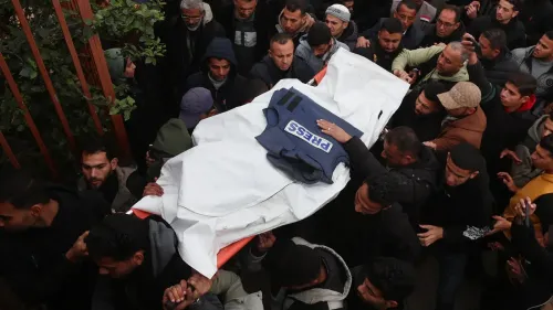 تجمع حشد من الناس حول نعش مغطى بعلم يحمل شعار "صحافة"، في مشهد يعكس الحزن بعد مقتل ثلاثة صحفيين فلسطينيين في غزة.