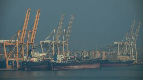 تظهر الصورة سفن شحن راسية في ميناء مع رافعات تحميل، مما يعكس تأثير النزاع في إيران على حركة الشحن وأسعار النفط.