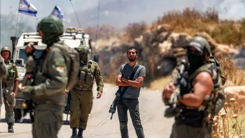 شاب يقف في مواجهة جنود إسرائيليين خلال مواجهة في منطقة متوترة، مع وجود مركبات عسكرية وأعلام إسرائيلية في الخلفية.