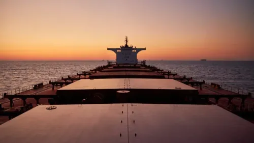 سفينة شحن كبيرة تبحر في البحر خلال غروب الشمس، مع التركيز على سطحها الفارغ، في سياق نقل النفط والفحم إلى إسرائيل.