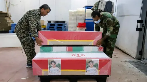 رجال يرتدون زيًا عسكريًا يقومون بحمل توابيت ملونة بأعلام إيران، تحمل صور أطفال، في مكان مخصص لتجهيز الجثامين بعد الهجوم على مدرسة البنات.