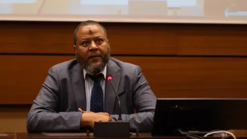 رجل سوداني يتحدث في مؤتمر، يعبر عن قلقه بشأن الانتهاكات المرتبطة بقوات الدعم السريع، ويطالب بالتحقيق في الجرائم المرتكبة.