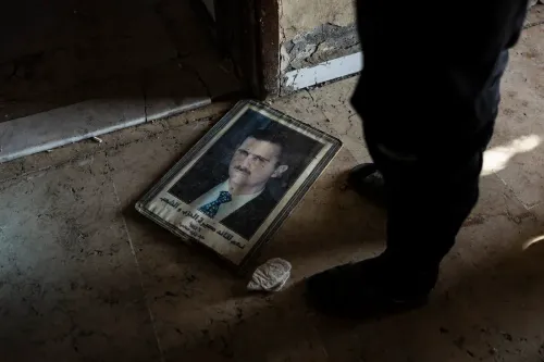 صورة لملصق تالف يظهر صورة بشار الأسد على الأرض، مما يعكس آثار الصراع في سوريا وتدهور الوضع السياسي.