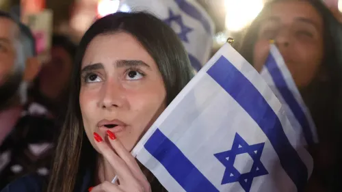 امرأة تحمل علم إسرائيل وتظهر تعبيرات القلق أثناء تجمع حاشد، تعكس ردود الفعل المتزايدة على الاتفاق المقترح مع إيران.