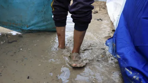 أقدام طفل تسير في مياه راكدة داخل مخيم للنازحين في غزة بعد هطول أمطار غزيرة، مما يهدد سلامة آلاف العائلات.