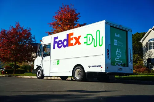 شاحنة توصيل كهربائية بيضاء تحمل شعار FedEx وشعار Harbinger، تعكس التحول نحو أساطيل شحن كهربائية في قطاع النقل.