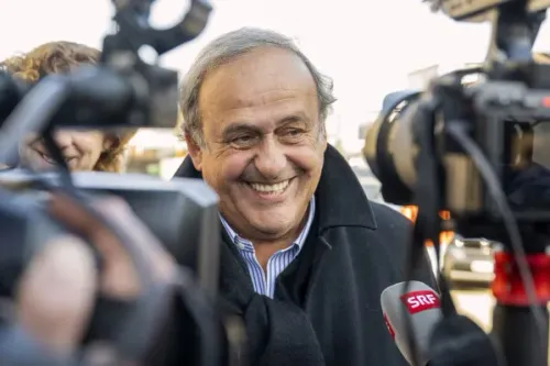 ميشيل بلاتيني مبتسم أثناء حديثه مع الصحفيين، في سياق الشكوى القانونية ضد رئيس FIFA جياني إنفانتينو ومسؤولين آخرين.
