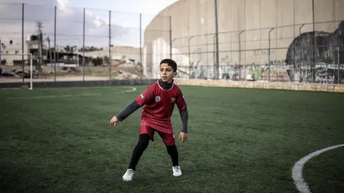 طفل فلسطيني يرتدي زي كرة القدم، يتدرب على ملعب عايدة المحاط بجدار الفصل، الذي يُستخدم من قبل أكاديمية كرة القدم المحلية.