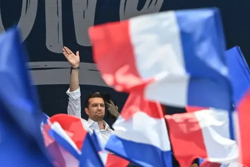 شخص يرفع يده في تجمع سياسي، محاط بأعلام فرنسية، في سياق التحذيرات من التدخل الأجنبي في الانتخابات الفرنسية.