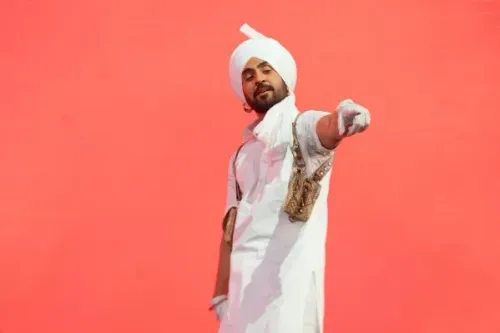 ديلجيت دوسانجه يرتدي زيًا تقليديًا ويؤدي على المسرح في مهرجان كوتشيلا، مع خلفية حمراء، معبرًا عن ثقافة البنجاب الموسيقية.