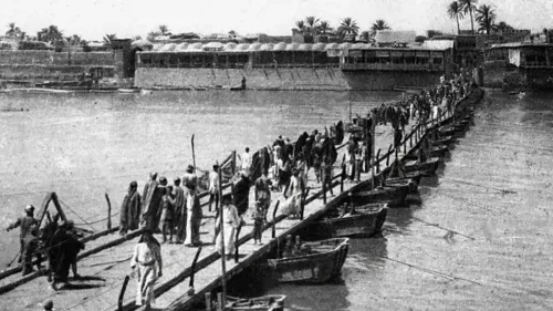 صورة تاريخية تظهر جسرًا خشبيًا يعبر نهر دجلة، حيث يتجمع الناس حوله، مع بواخر في المياه، تعكس أهمية التجارة والنقل في العراق.