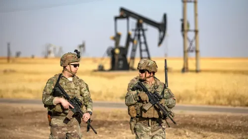 جنود أمريكيون يسيرون بالقرب من منصة نفطية في منطقة صحراوية، مما يعكس التوترات العسكرية حول السيطرة على الموارد النفطية.