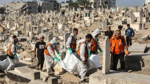عمال إنقاذ يحملون جثثًا في مقبرة مدمرة بغزة، وسط أضرحة مدمرة، في سياق جهود التعافي بعد النزاع.