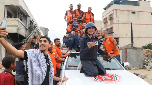 مجموعة من الأشخاص يرتدون زي الإنقاذ، يلتقطون صورًا معًا فوق سيارة إسعاف في غزة، تعبيرًا عن الأمل بعد إعلان وقف إطلاق النار.