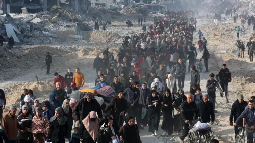 مئات من الفلسطينيين يسيرون عبر أنقاض مدينة غزة، يحملون الأمتعة وسط سحب من الغبار، معبرين عن معاناتهم في ظل الحرب.