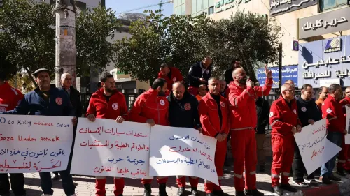 تجمع أفراد من الهلال الأحمر الفلسطيني في مظاهرة، حاملين لافتات تعبر عن استنكارهم لاستهداف طواقم الإسعاف في غزة.
