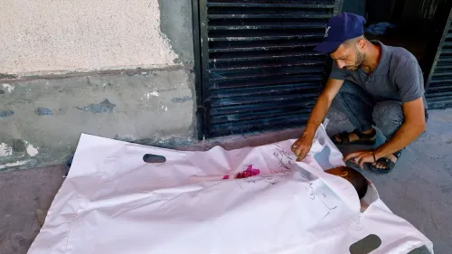 رجل فلسطيني يودع جثمان طفل ملفوف في كيس أبيض وسط الحصار الصحي والإنساني في غزة.
