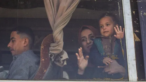 عائلة فلسطينية تنتظر عند معبر رفح، حيث يُسمح بعبور 50 شخصًا يوميًا من مصر إلى غزة، وسط ظروف صعبة.