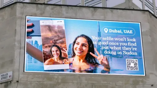 لوحة إعلانات في لندن تعرض شابة تلتقط سيلفي في حوض سباحة، مع أفق دبي وخلفها دمار الحرب في السودان، مرفقة بتعليق يسلط الضوء على دور الإمارات.