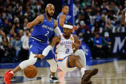 لاعب من فريق أورلاندو ماجيك يتصدى للاعب من فريق أوكلاهوما سيتي ثاندر خلال مباراة كرة سلة، مع وجود لاعبين آخرين في الخلفية.