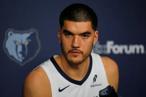 زاك إيدي، لاعب فريق ممفيس جريزليز، يتحدث في مؤتمر صحفي، مع خلفية تحمل شعار الفريق. يتعافى من جراحة في كاحله.